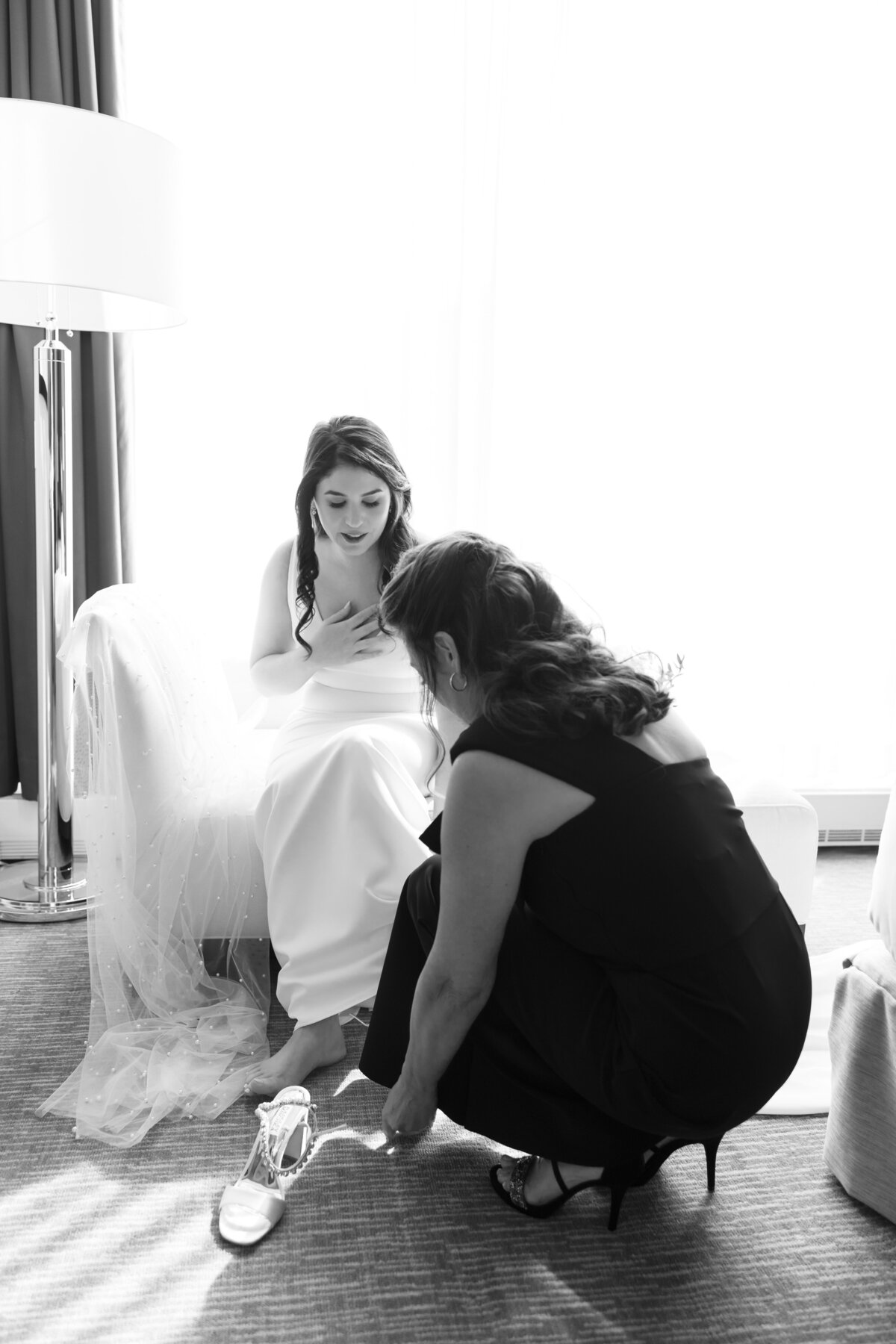 Bride getting her shoes on with her mom