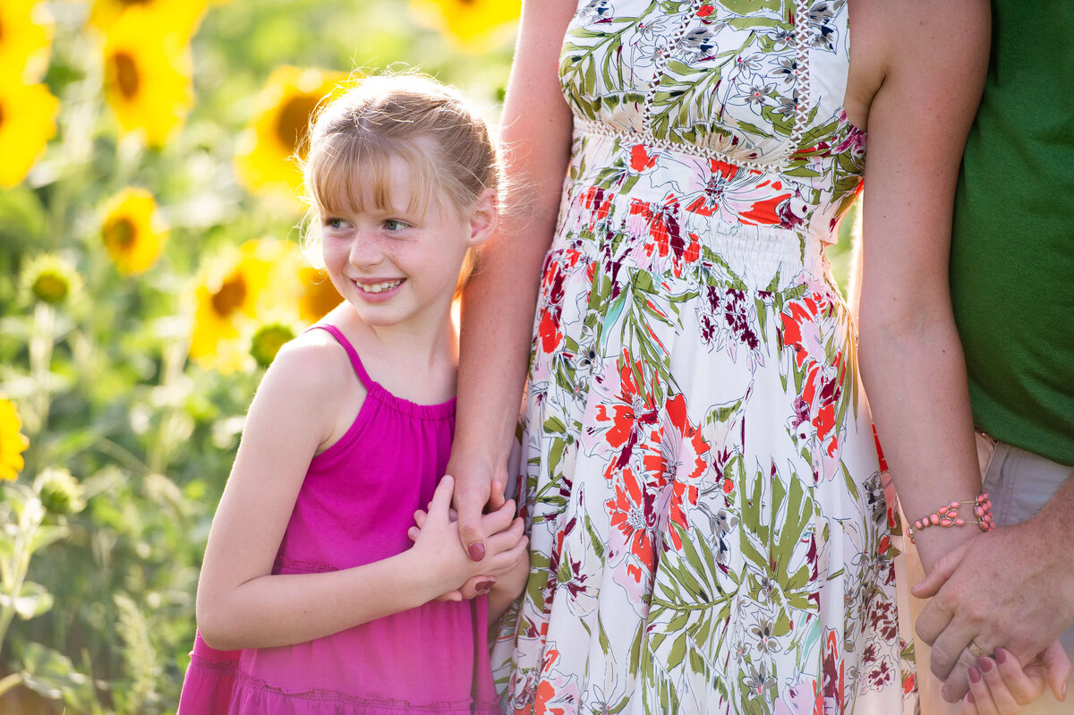 a little girl holds her mom's hand in a sunflower field at sunset taken by Ottawa Family Photographer JEMMAN Photography