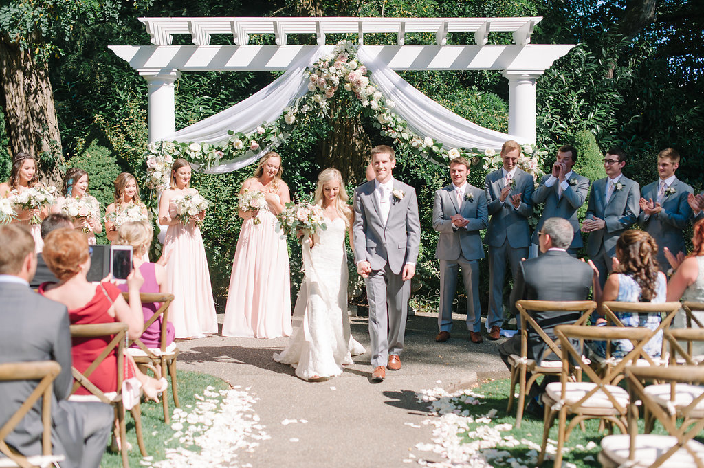 Aisle lined with rose petals lead up to the arch at this lovely outdoor garden wedding ceremony.