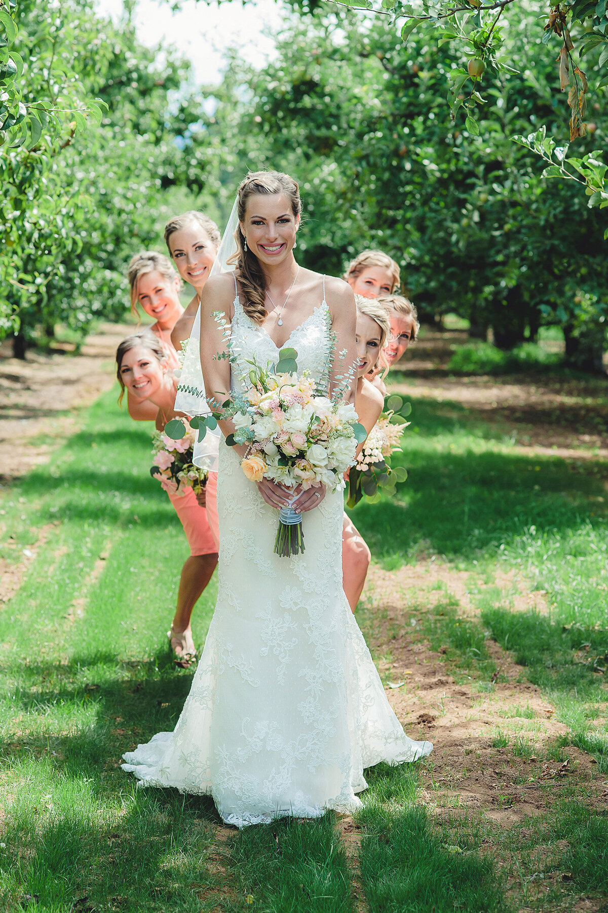 bridesmaids behind bride in orchard