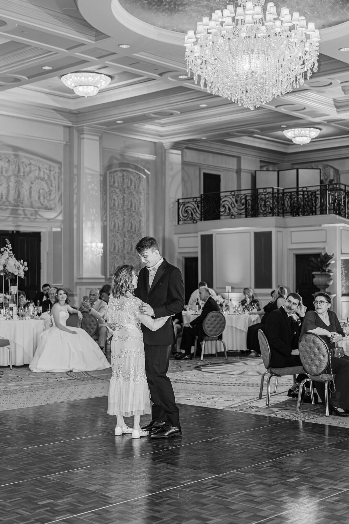 A groom dancing on hsi wedding day with his mom under a chandler enjoying their Raleigh wedding photos