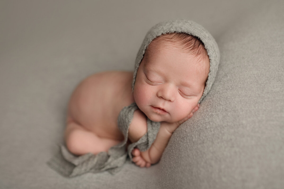 Sleeping newborn baby in gray bonnet