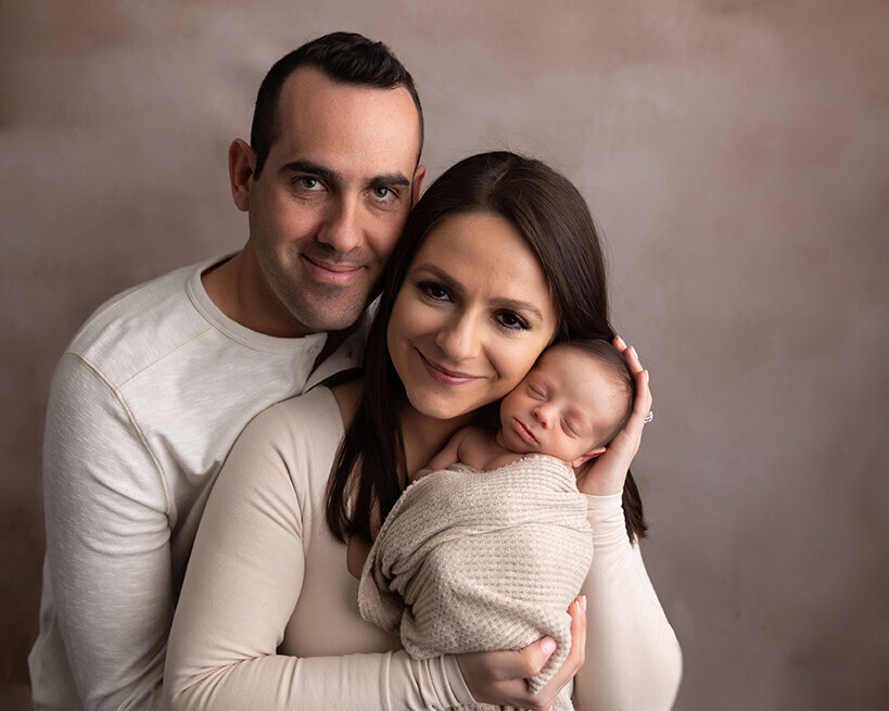 Mom and dad holding son and smiling posed in greensburg photography studio.