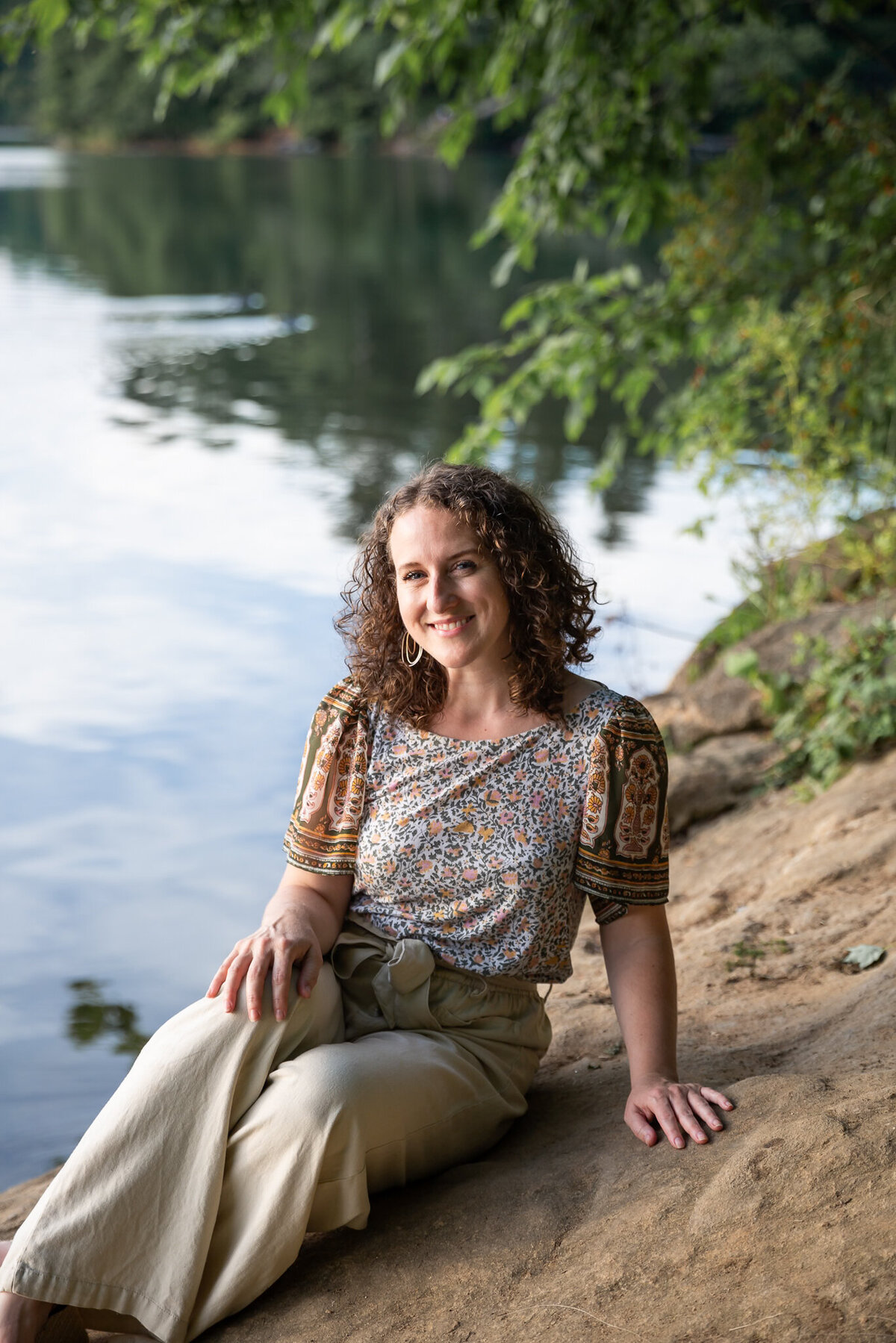 A creative write poses for a headshot near a lake during her personal branding photoshoot.