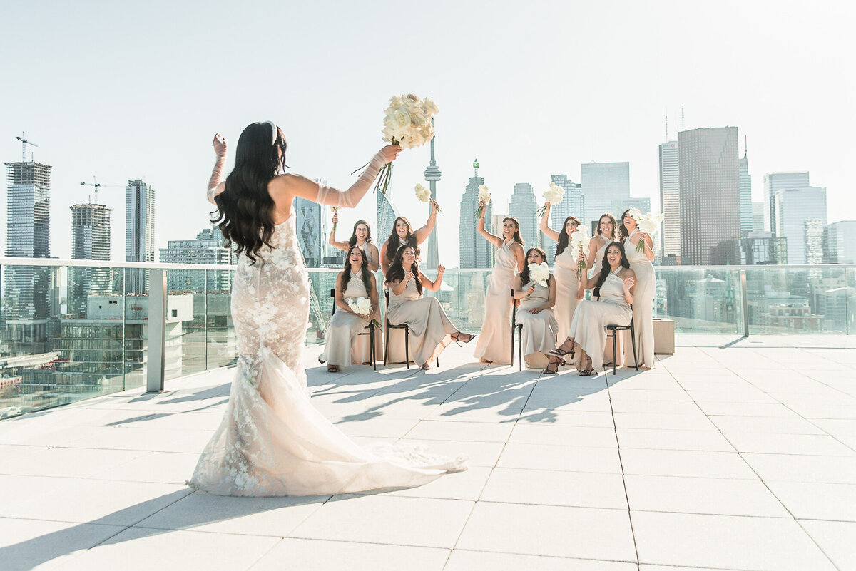 Bride is facing away from the camera and cheering and celebrating with her group of bridesmaids at The Globe and Mail Centre in Toronto