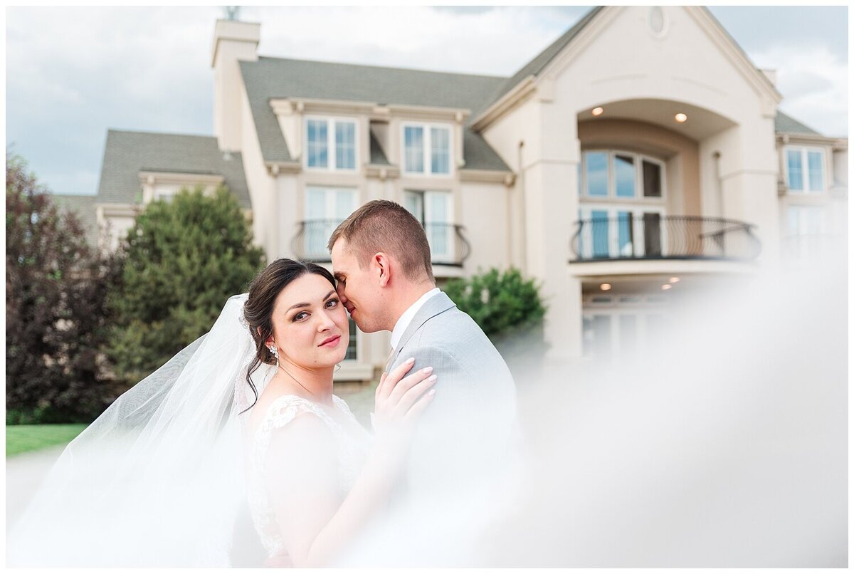 Veil shot crossing the frame with bride and groom in the background, bride looking at Denver wedding photographer and groom nuzzling the bride's temple