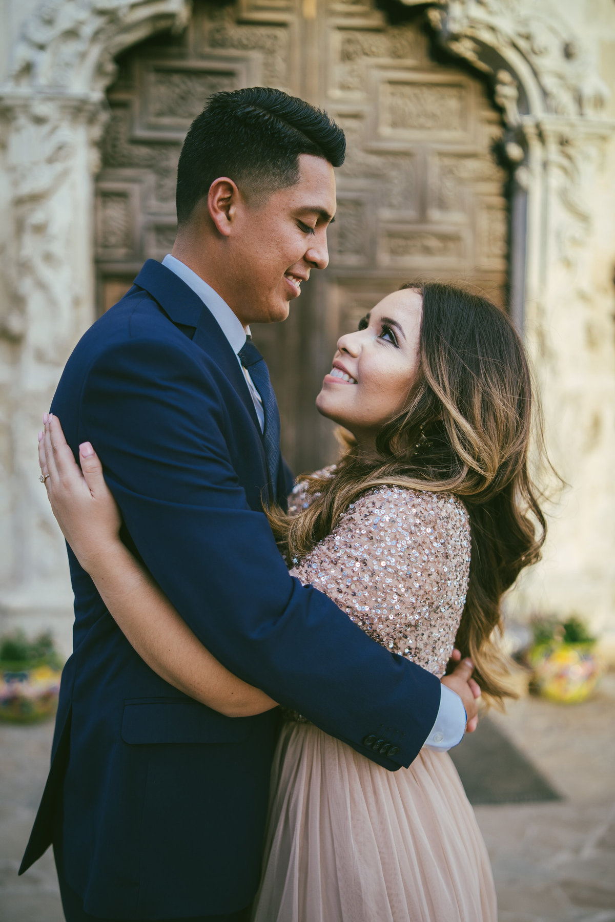 Couple embracing in front of Mission San Jose door on their engagement session.