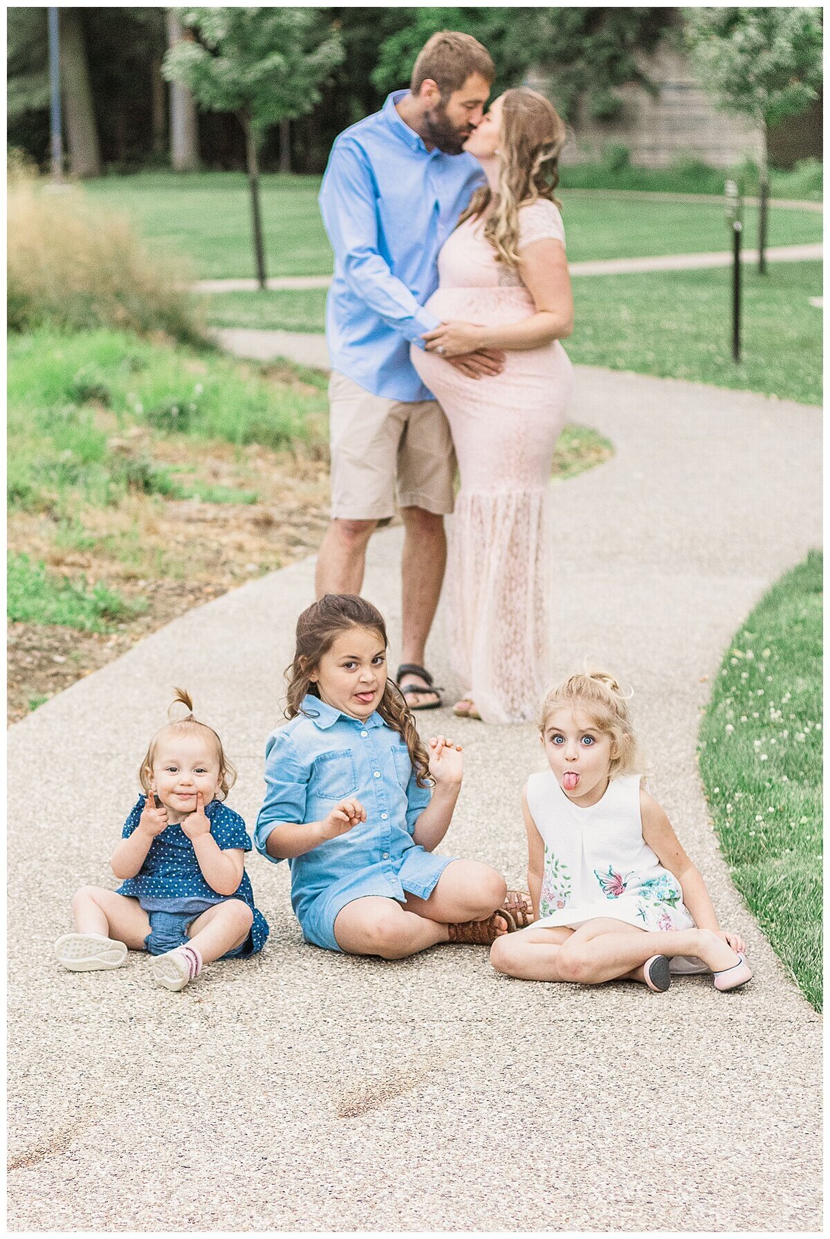 an outdoor Maternity Photography in Wexford where mom and dad sneak in a kiss and their three kids are in the front making faces