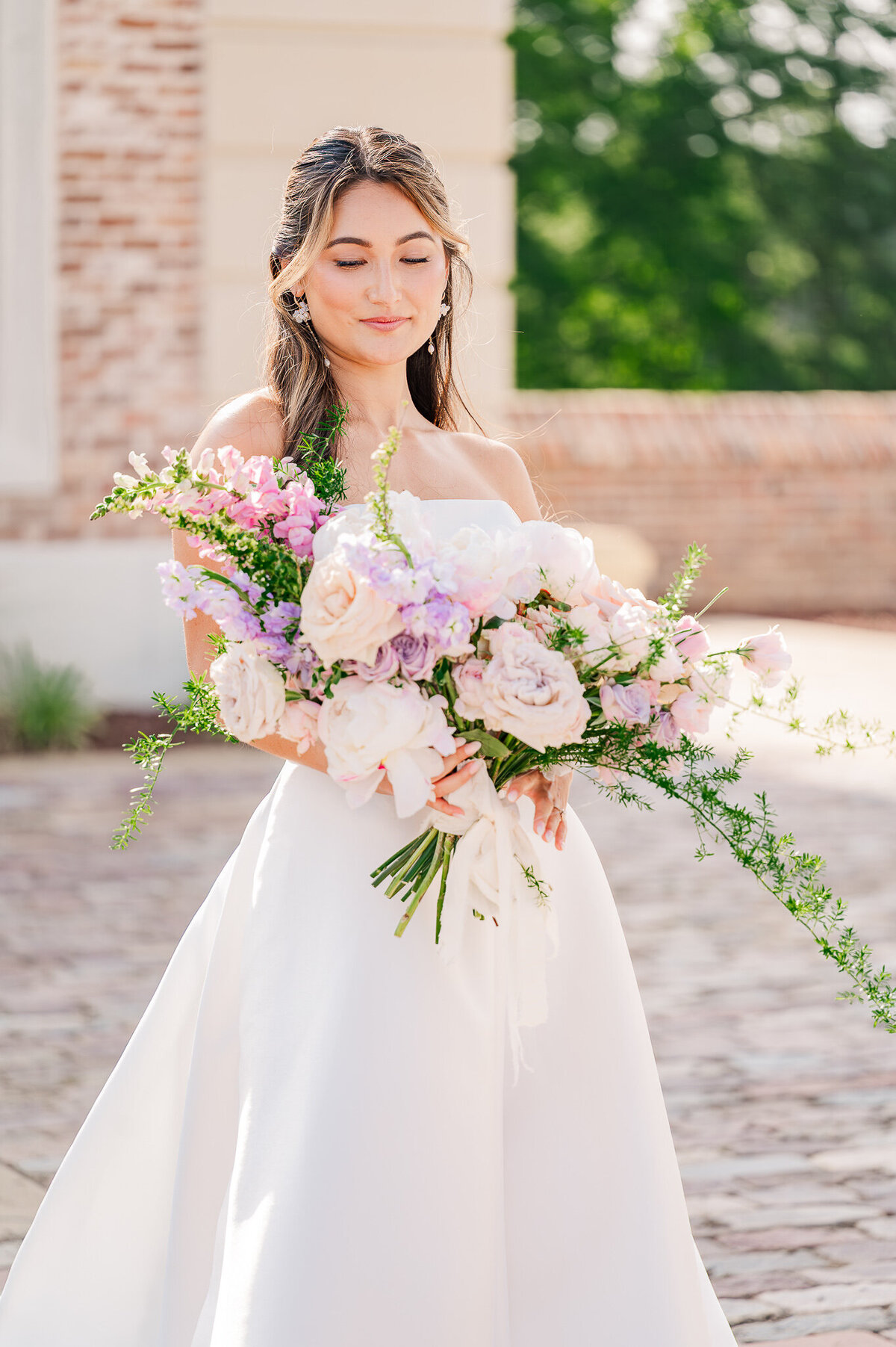 A brunette bride having her bridal portraits at The Oxbow Estate while holding a lavender wedding bouquet while enjoying her Raleigh wedding photography session by JoLynn Photography