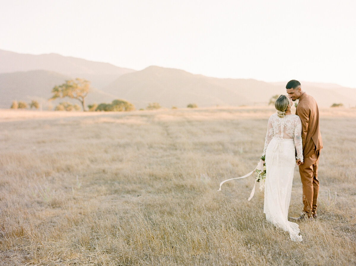 a bride and groom walking off into the sunset in a large field in california at kestrel park