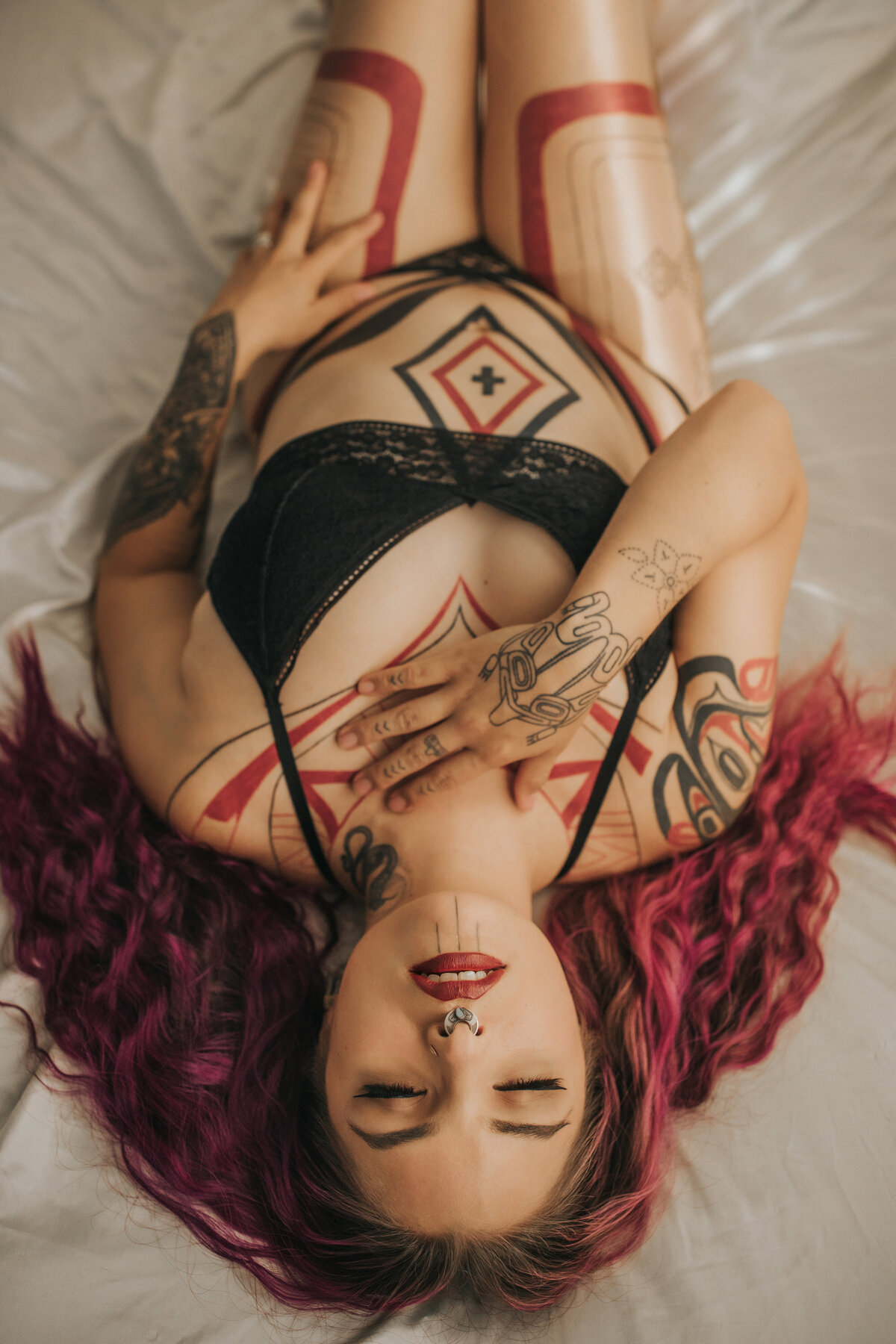 indigenous tattooed model posing on bed in boudoir photography studio