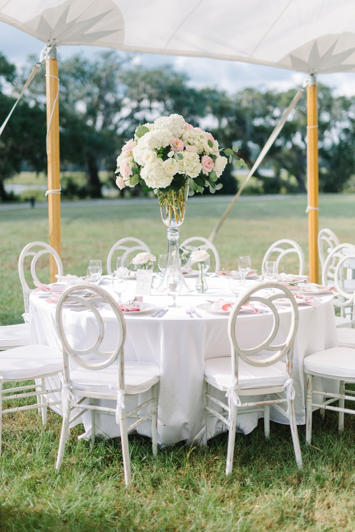 White and Blush Wedding Reception with Tall Hydrangea Centerpiece and White Chloe Chairs  under Sailcloth Tent at Boone Hall