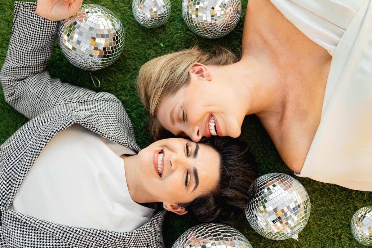 Couple lying on the ground together with disco balls around them.