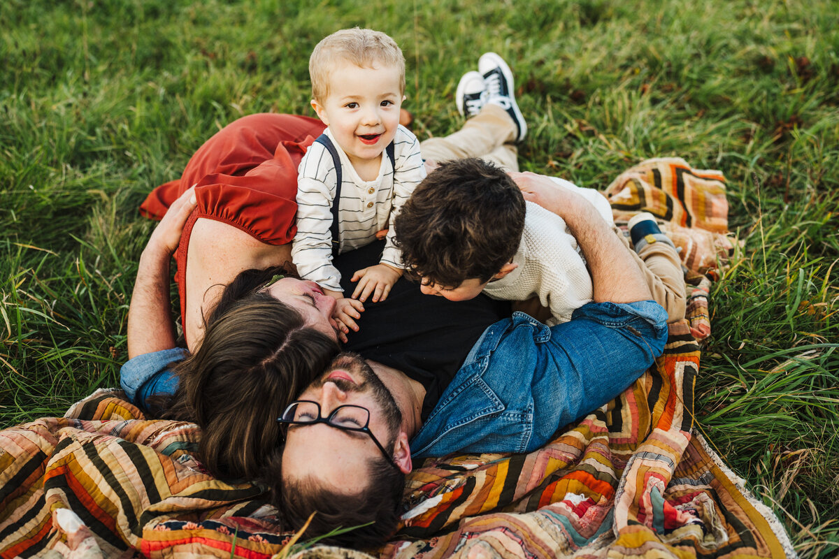family lies on blanket in boston park