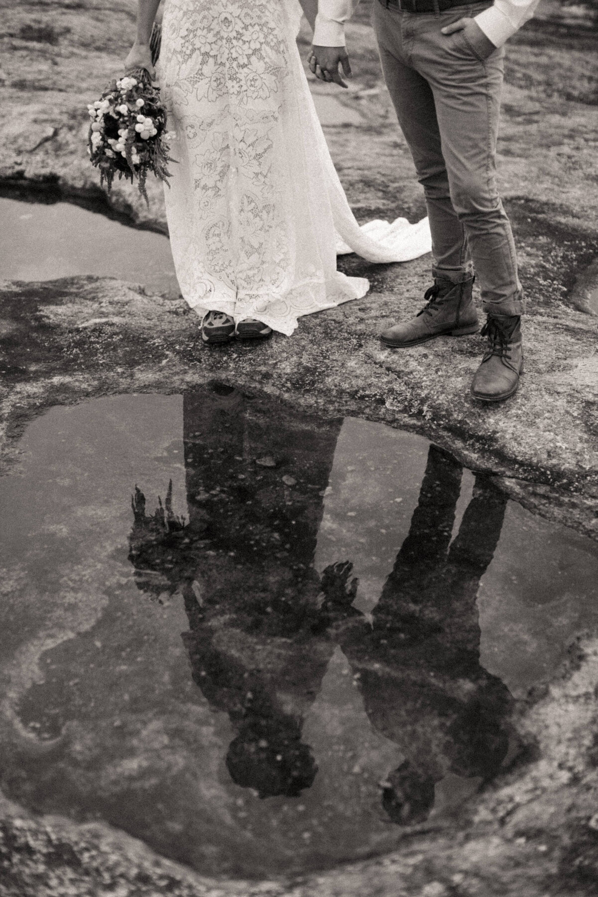 Reflection of bride holding bouquet and groom in water