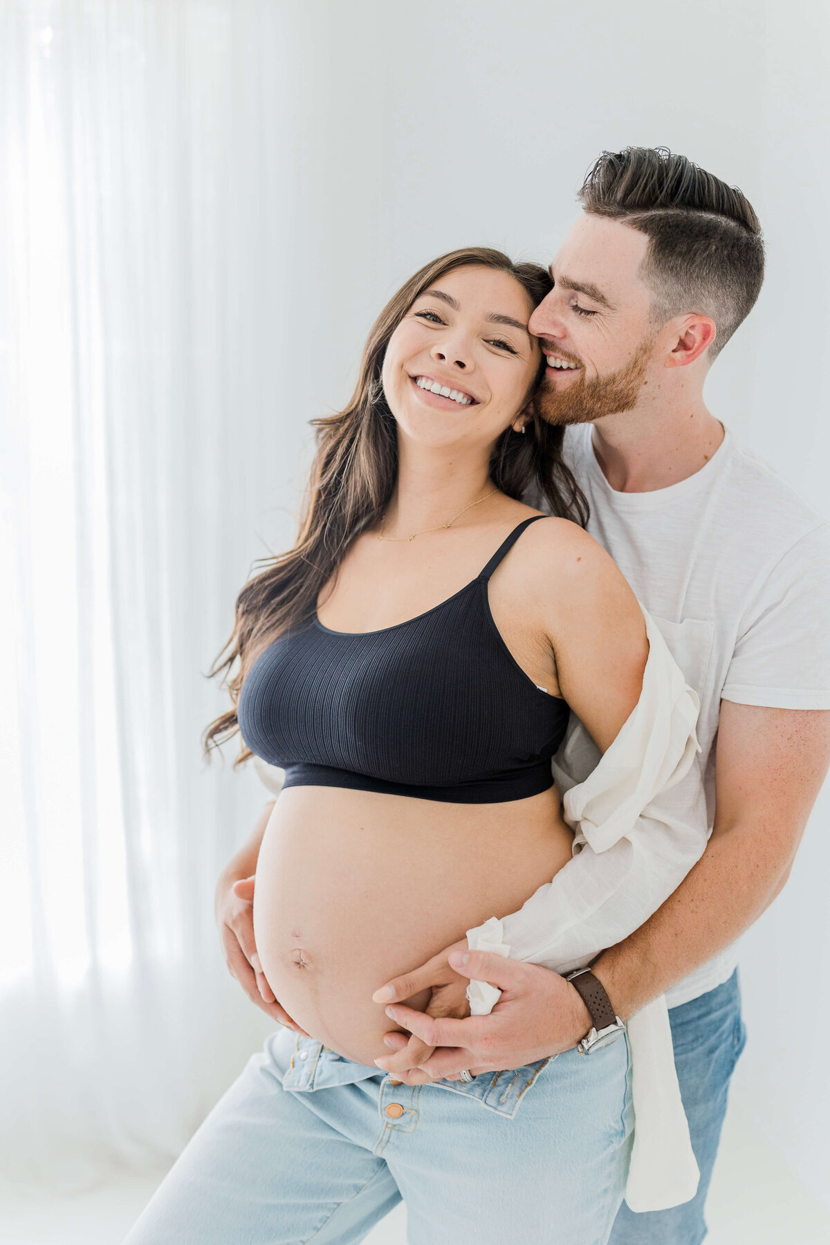 Couple snuggling together during their maternity photoshoot