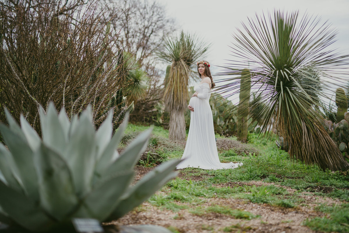 woman in boho maternity dress surrounded by succulents for her San Antonio maternity photography session at Botanical Garden