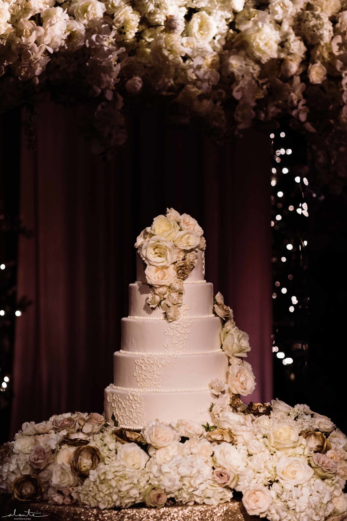White tired wedding cake surrounded by white flowers.