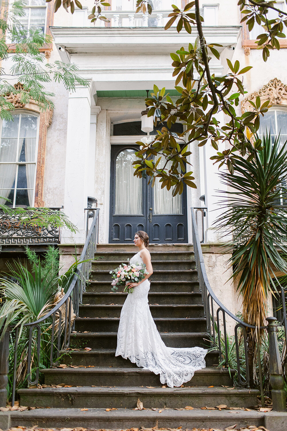 Bride standing on stairs holding bouquet.