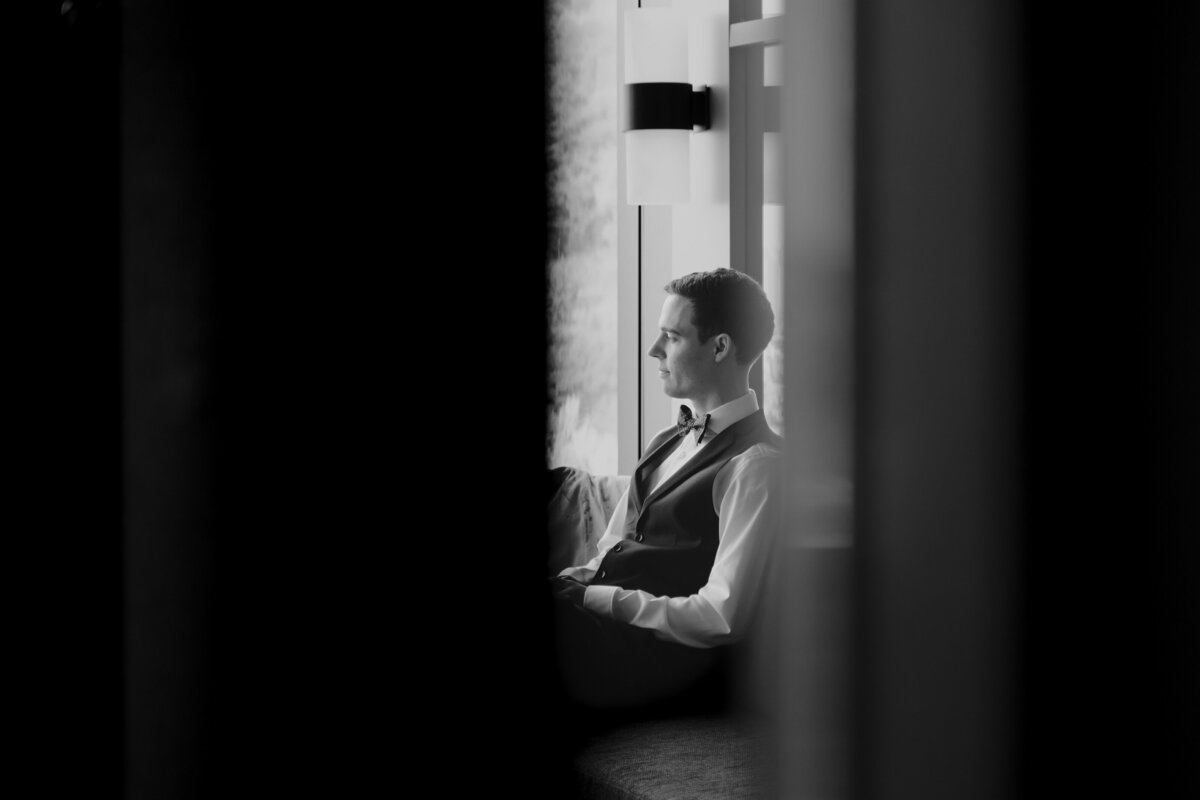 the groom is sitting by the window looking outside