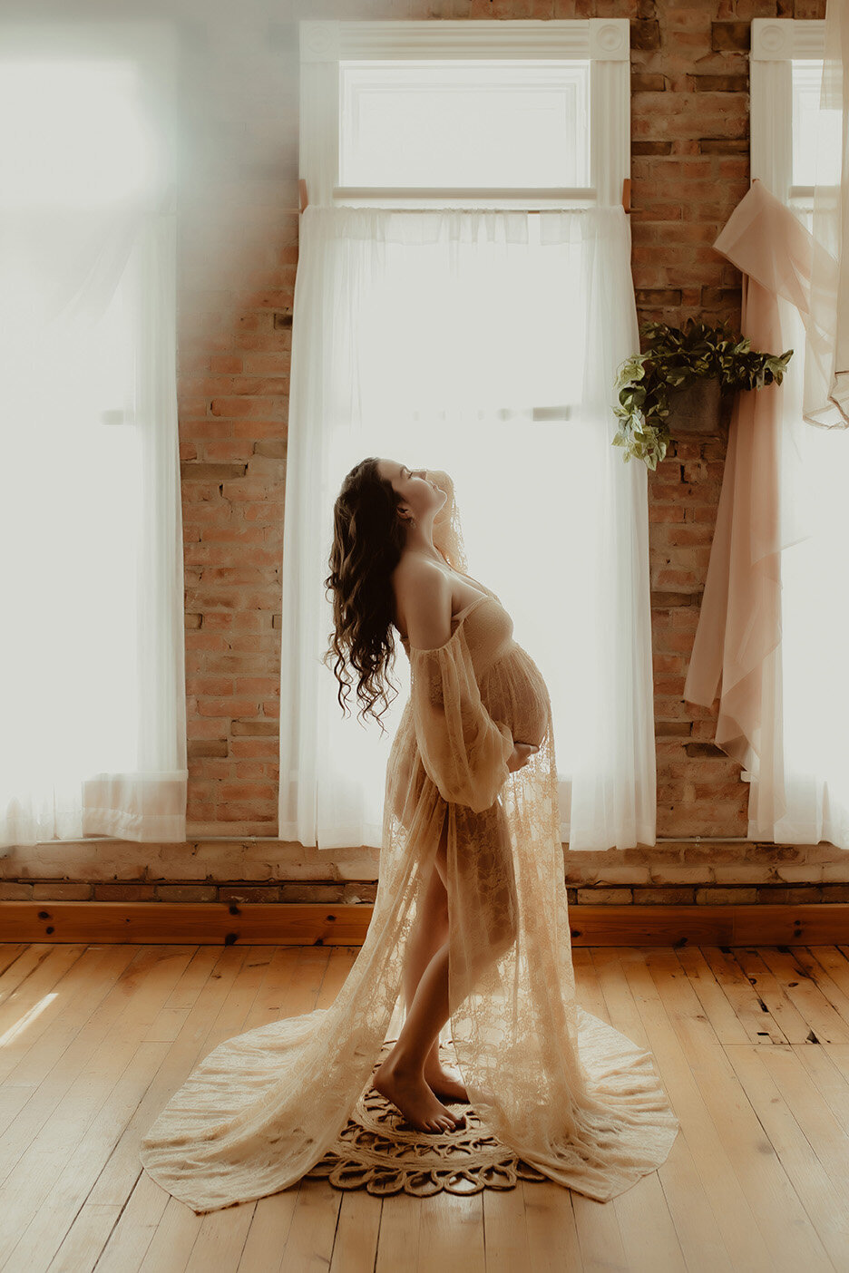 a beautiful pregnant woman holding her bump in a natural light setting
