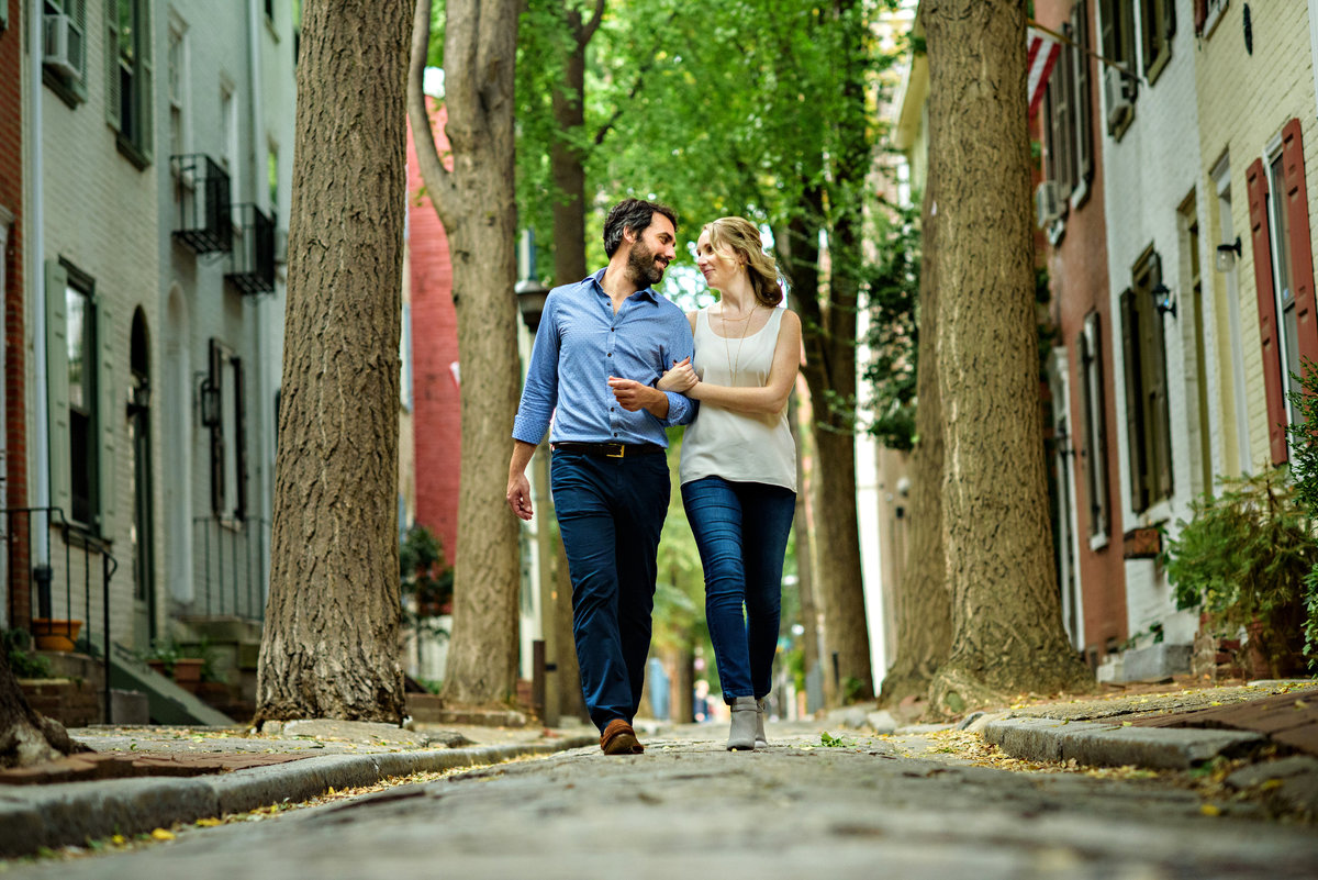 A fun couple walk the cobblestone streets of center city philly.