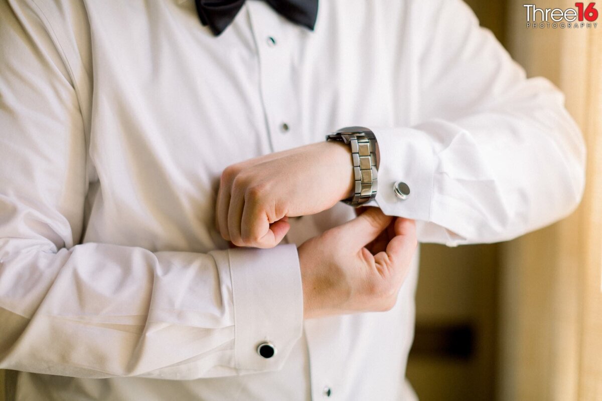 Groom adjusting his cuff links prior to the ceremony