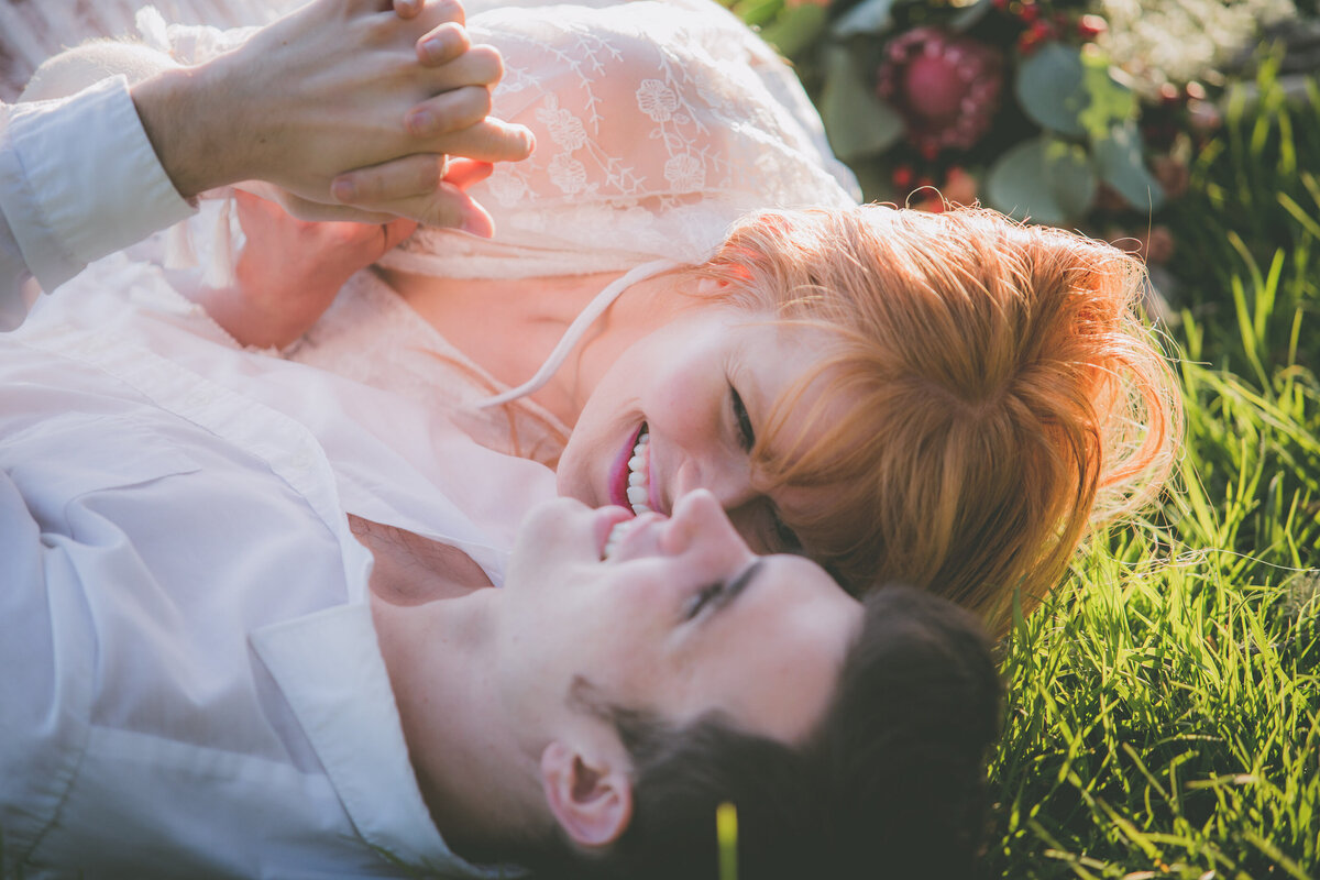 Closeup of couple laughing in grass.