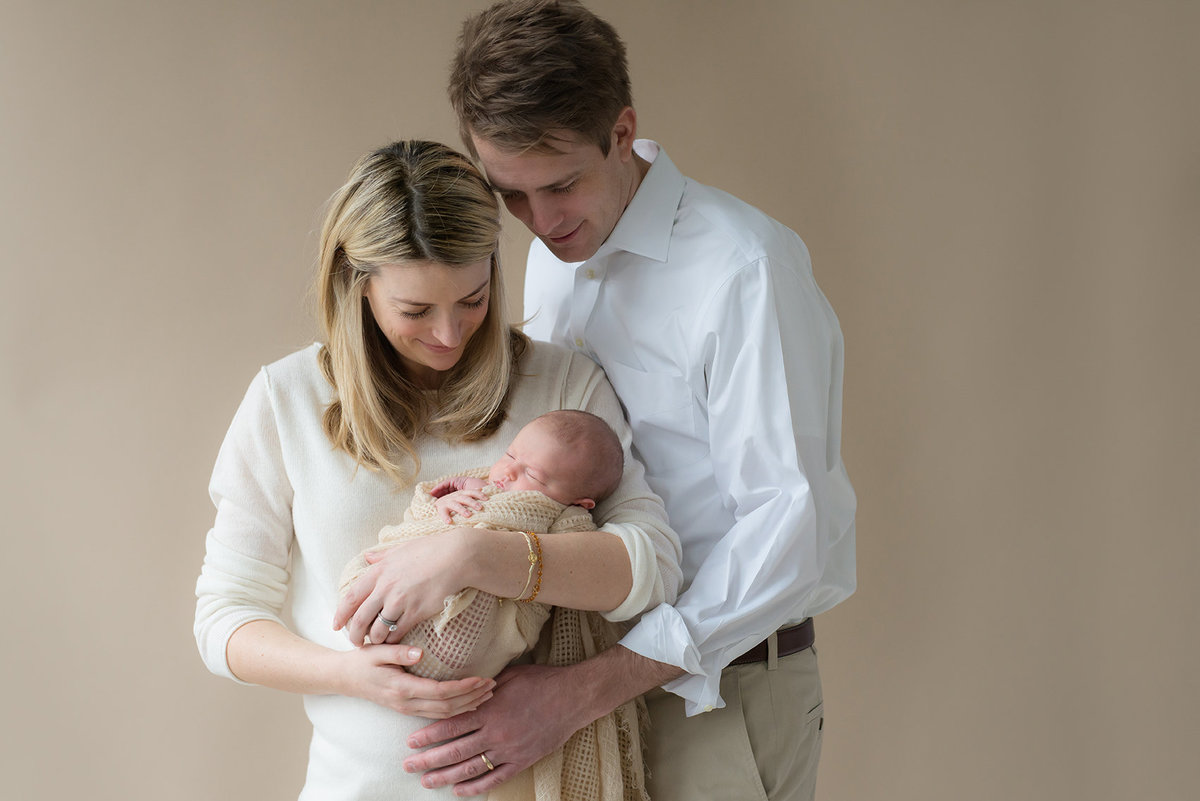 new parents hold their new baby in a studio
