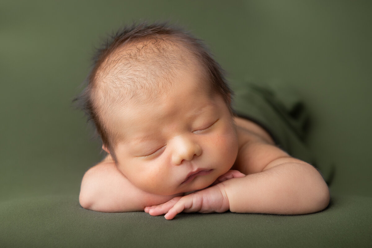 Olive green chin on hands studio table newborn pose
