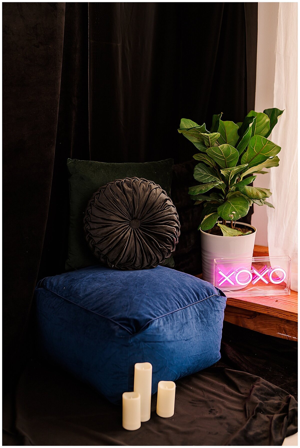 Dark and gemtoned photography studio scene with neon sign and candles