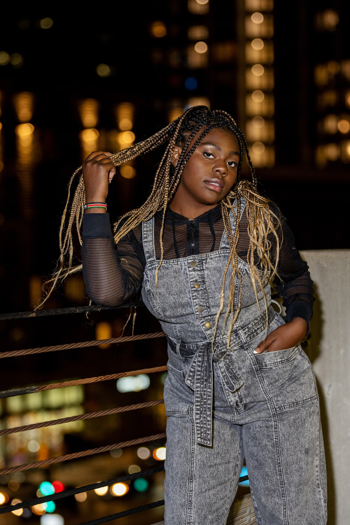 senior photo of girl in jumpsuit against parking garage wall in minneapolis at night