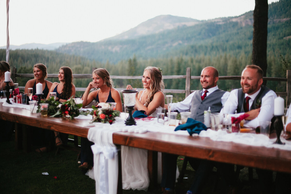 Bride, groom, and wedding party sit at wedding reception overlooking Lake Tahoe