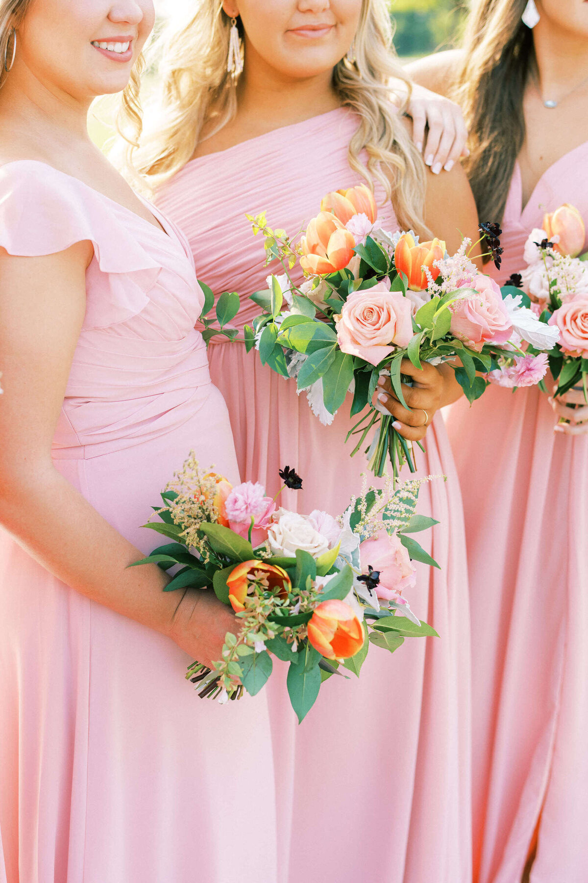 Light pink bridesmaids dresses and orange and blush bouquets