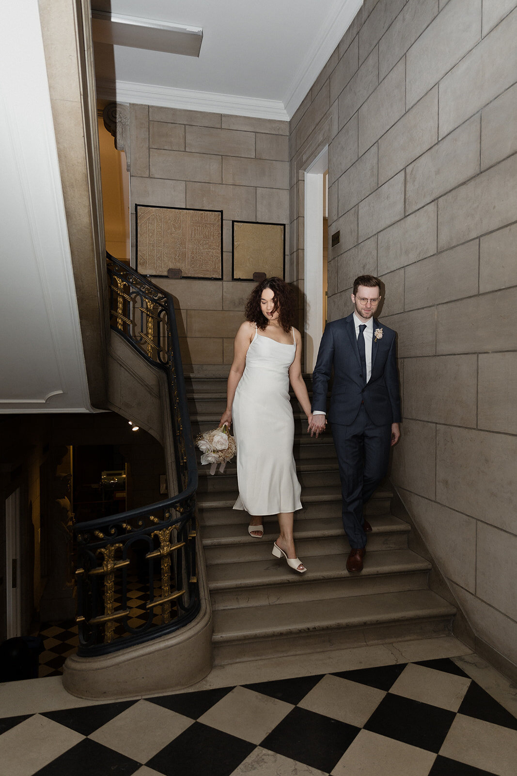 Just Married photo session couple walks down staircase, flooring is large checkboard pattern at International Museum of Surgical Science