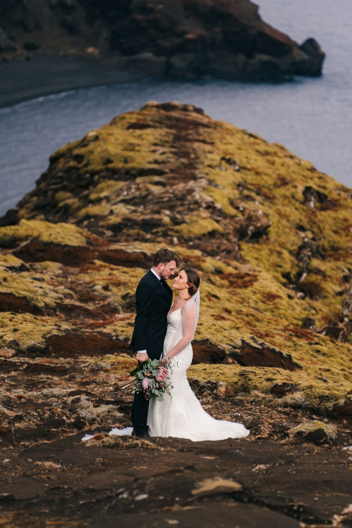 Face to face, this couple shares a mesmerizing gaze against the stunning backdrop of the Icelandic coast, where love meets the endless horizon.