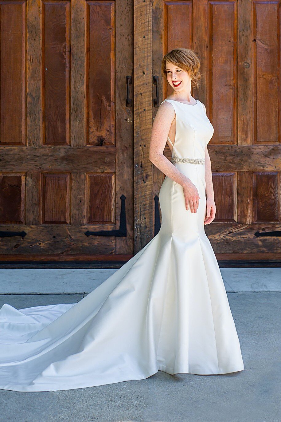 The side view of the Eva wedding dress style shows how the long train flows from the fit-and-flare mikado skirt to accentuate the curves of the body.