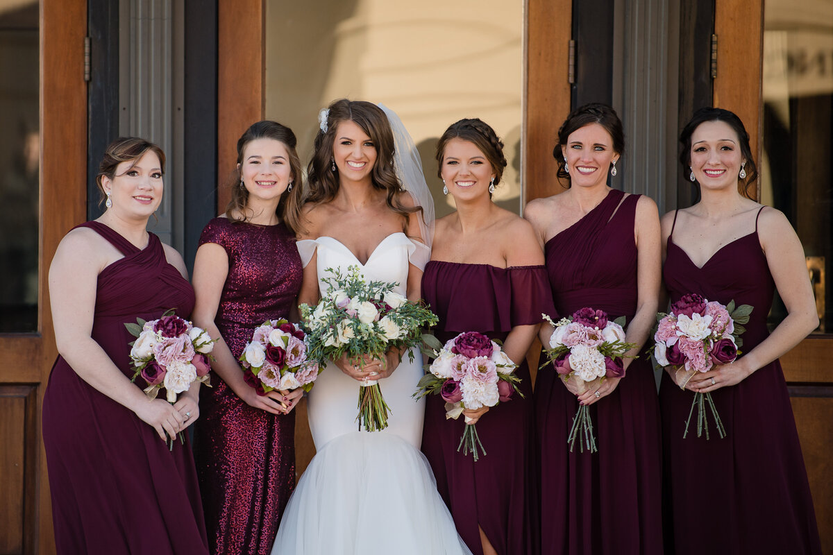 bride with bridesmaids in burgandy dresses in front of Blennerhassett hotel