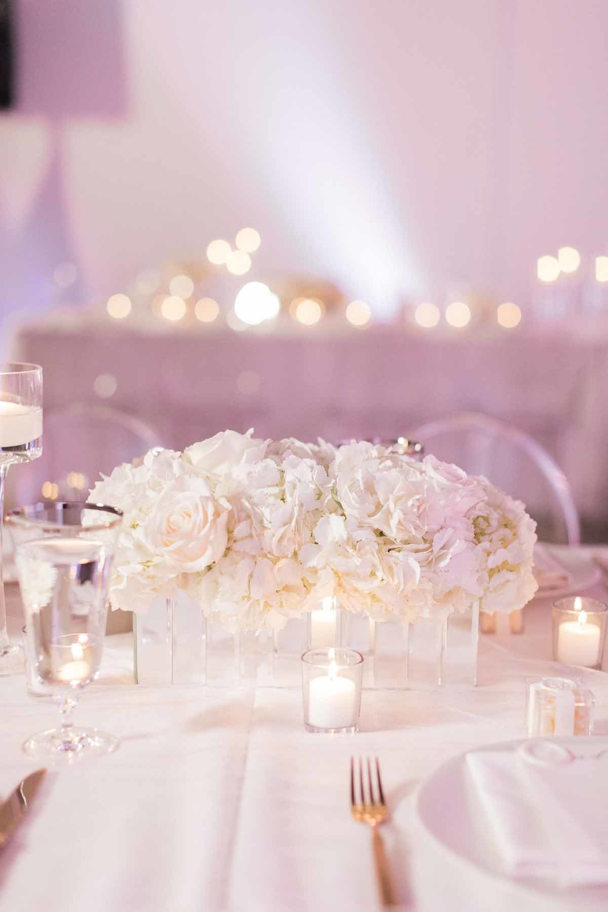 White hydrangea and rose arrangement lit by hundreds of candles is so romantic for a reception look.