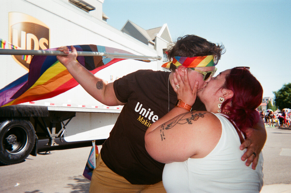 A couple kissing while holding a pride flag.