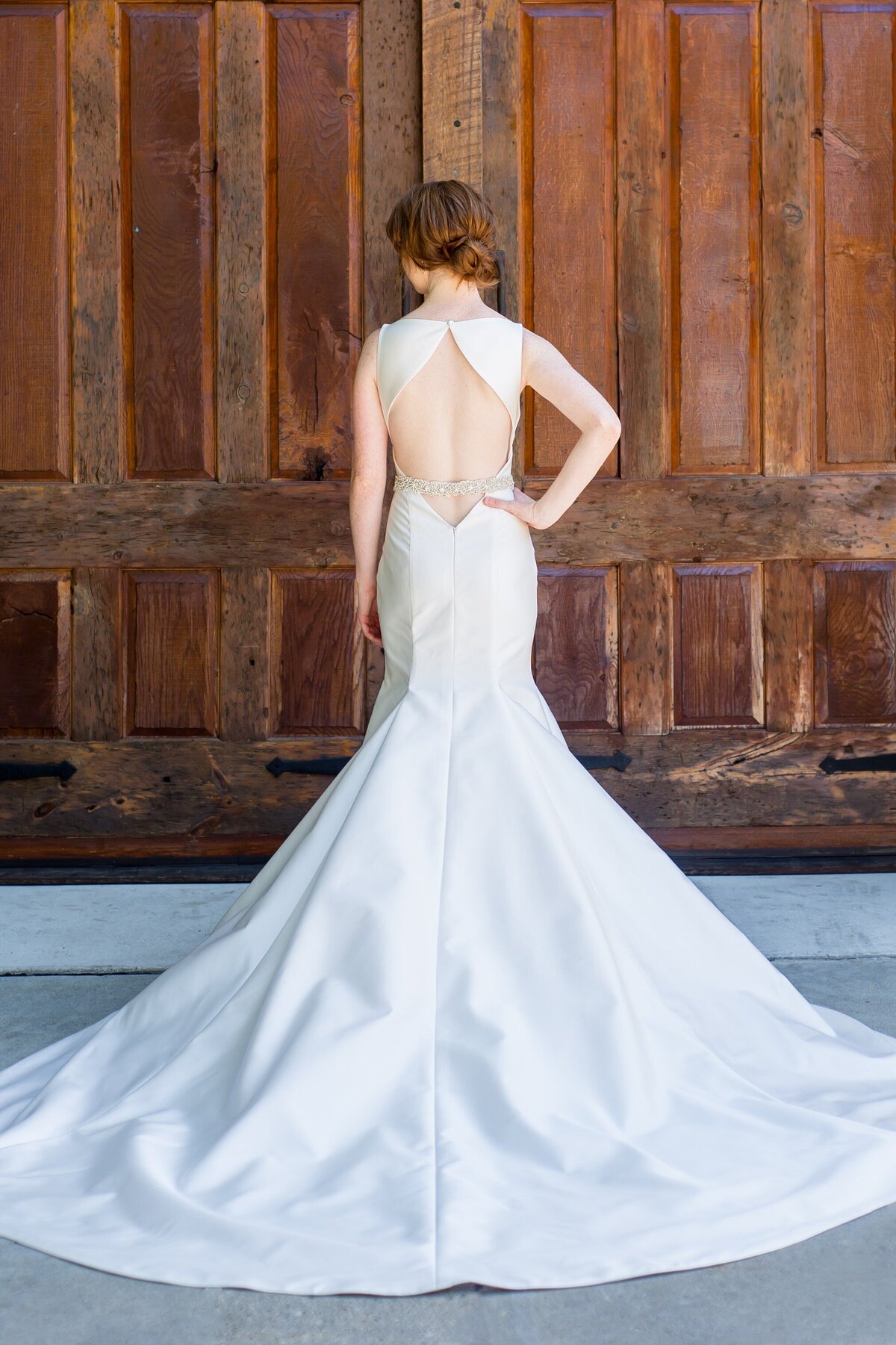 The low open keyhole back of the Eva bridal style with its diamond shape points to the long train of the fit-and-flare skirt.