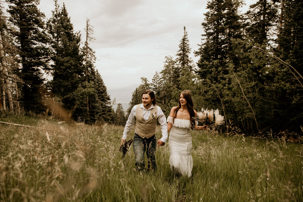newlyweds walking through a field of grass and the Sandia Mountain Peak in Albuquerque