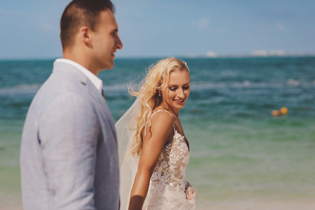 Bride and groom holding hands and waling on beach in Cancun