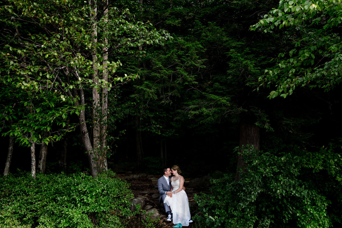 Dublin New Hampshire wedding the couple sits among the lush trees that look out at Mount Monadnock and laugh