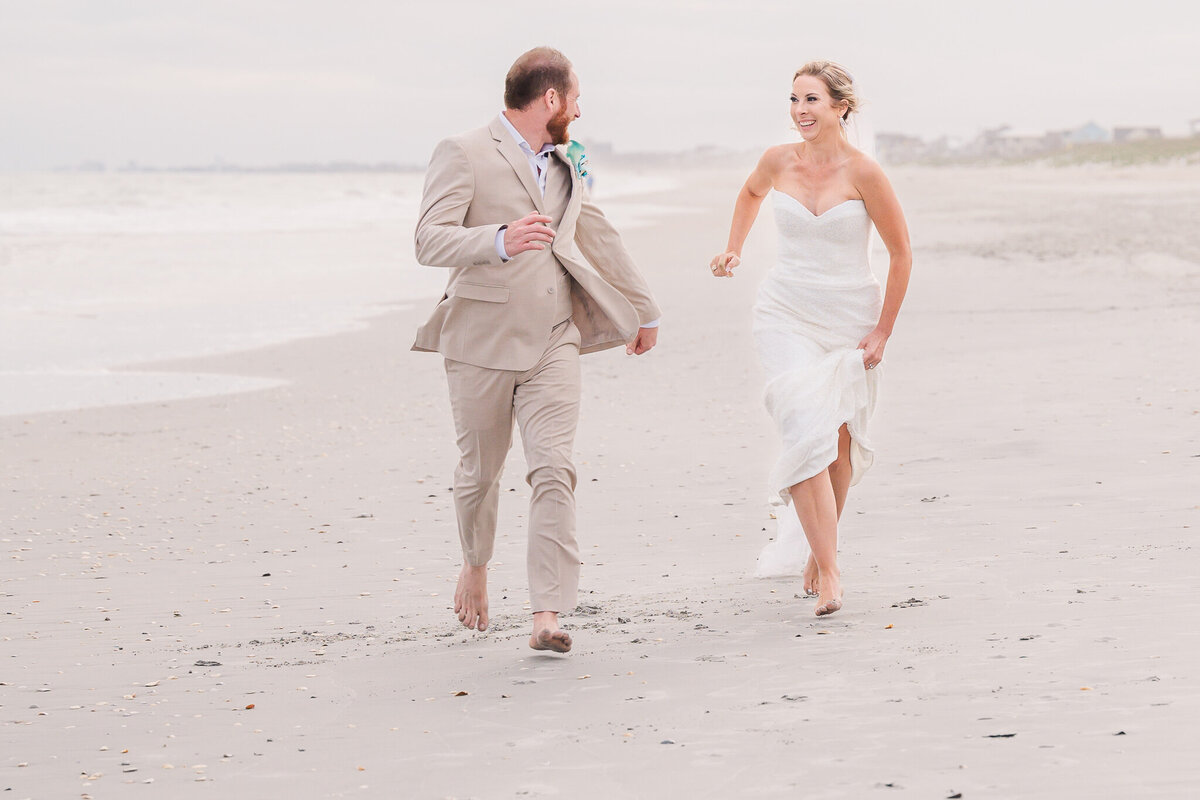 A happy married couple celebrating their wedding on the beach at sunset by Raleigh wedding photographer, JoLynn Photography
