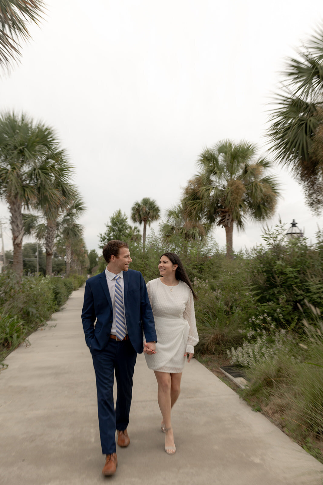 Couple walking on boardwalk at Colonial Lake Park with palms trees and greenery on both sides