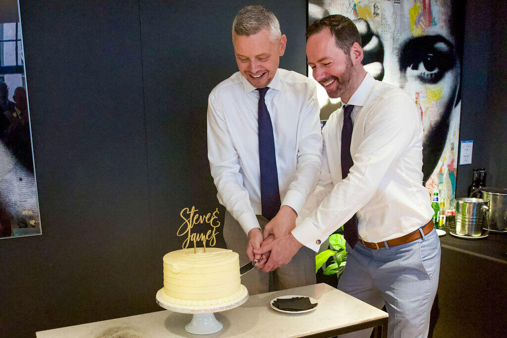 Two men cut wedding cake together.  Mercer hotel london