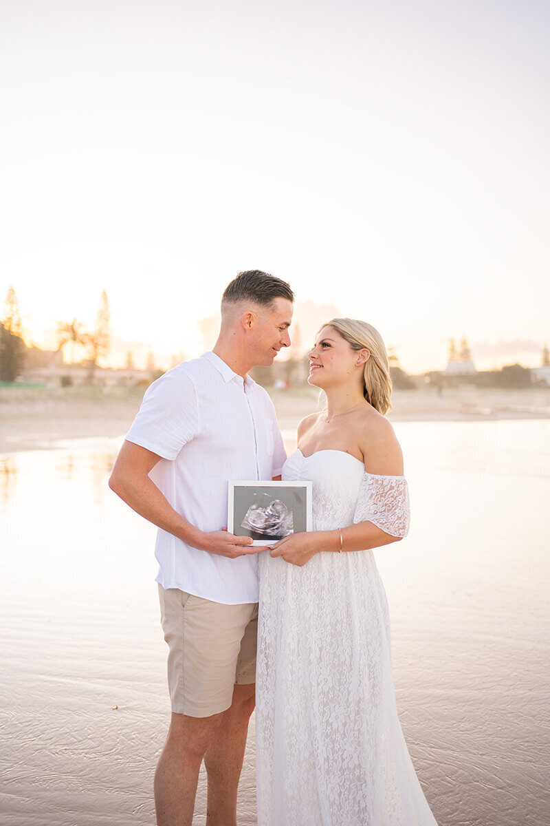 couple holding sonograph having maternity photos taken