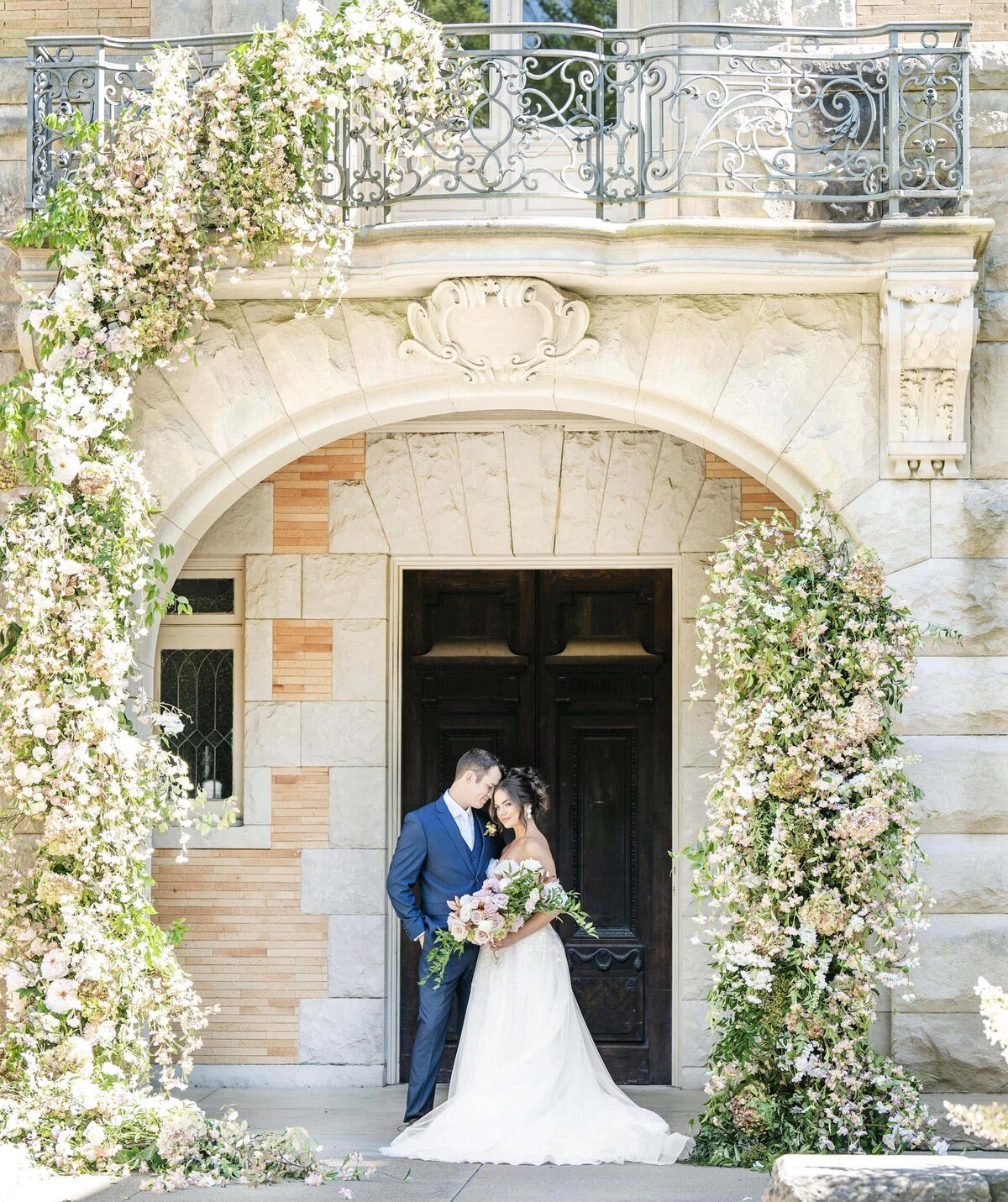 Bride and groom with floral arch installation