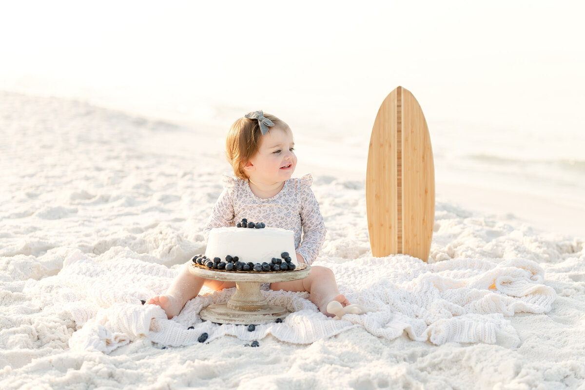 A family beach photographer captures a baby girl with a surfboard at Destin.
